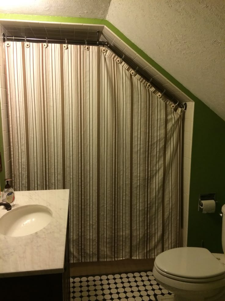 a bathroom with green walls and black and white checkered flooring on the tile