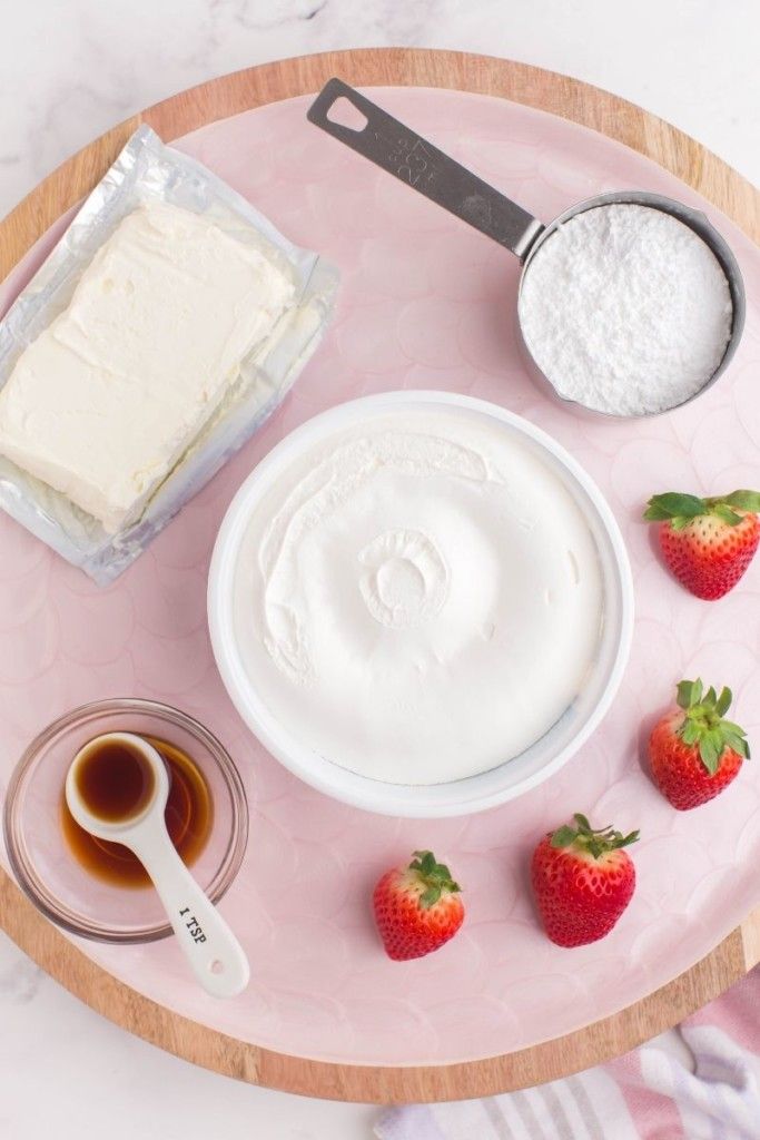 a plate with strawberries, cream and sugar on it next to a measuring spoon