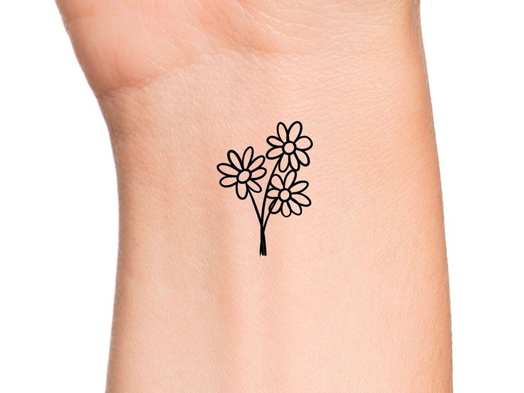 a small flower tattoo on the wrist is shown in black and white, as well as an outline of a tree