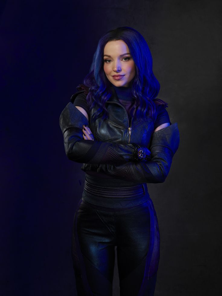 a woman with blue hair and black leather outfit posing for a photo in front of a dark background