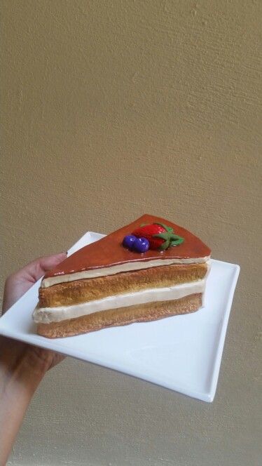 a piece of cake on a white plate being held by a person's hand