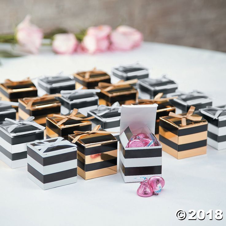 several boxes with pink and black candy in them sitting on a white tablecloth covered table