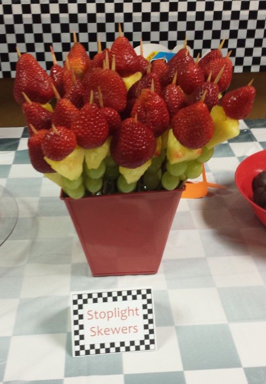 strawberries are arranged in a flower pot on a checkered tablecloth with a sign that says stoplight skewers