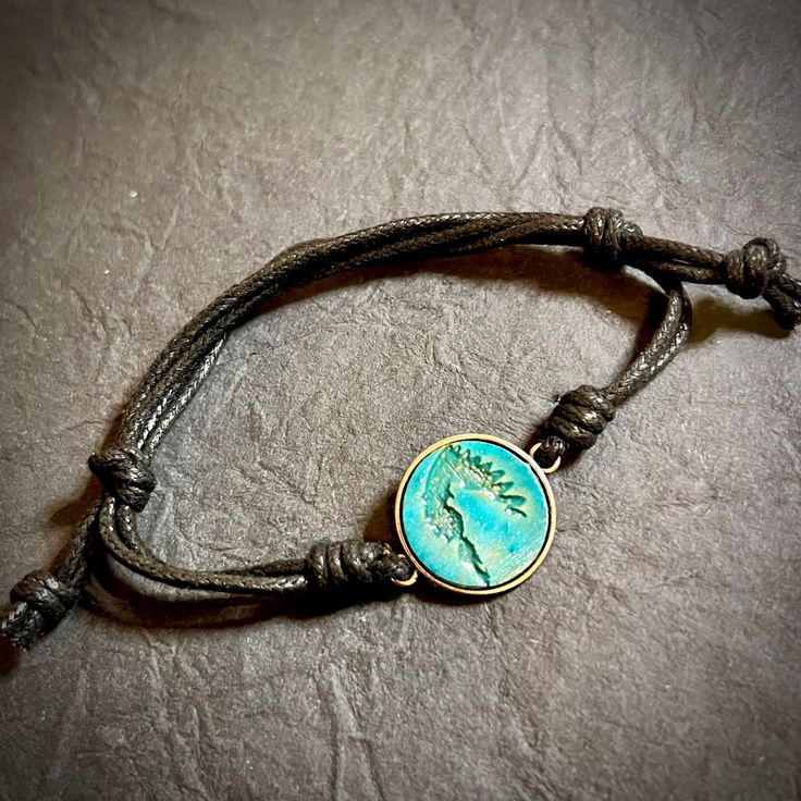 This beautiful Cherokee Nation bracelet is a unique piece of jewelry that embodies the spirit of the tribe. Crafted with a metal bezel and engraved wood, it is a stunning piece that is perfect for any occasion. The slip cord design adds a touch of rustic to the bracelet, making it a must-have for any jewelry collection. The bracelet is perfect for those who love nature, regional, and tribal jewelry, and it is sure to be a conversation starter wherever you go. Casual Metal Jewelry With Adjustable Cord, Adjustable Nature-inspired Bracelet Jewelry, Adjustable Nature-inspired Jewelry Bracelet, Nature-inspired Adjustable Bracelet Jewelry, Adjustable Nature-inspired Bracelet, Adjustable Turquoise Nature-inspired Jewelry, Nature-inspired Adjustable Round Jewelry, Adjustable Engraved Nature-inspired Jewelry, Adjustable Waxed Cord Jewelry For Friendship