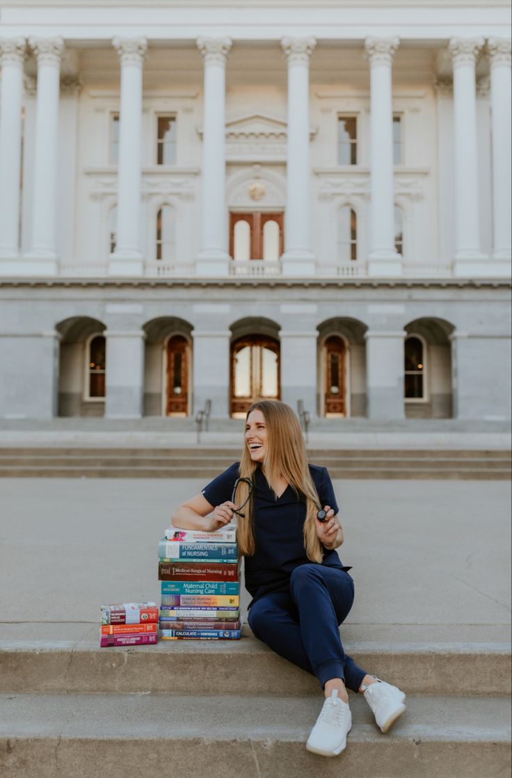 a woman sitting on the steps in front of a building with stacks of books next to her