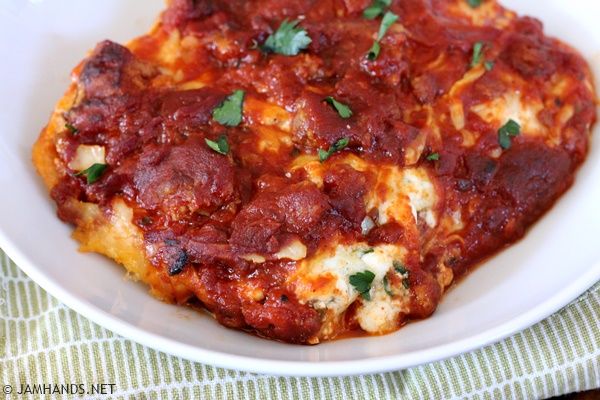 a close up of a plate of food with sauce and cheese on it next to a fork