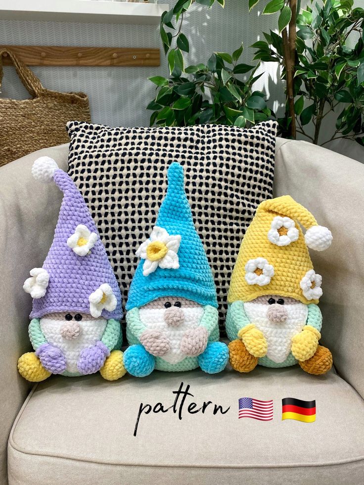 three crocheted gnomes sitting next to each other on a couch