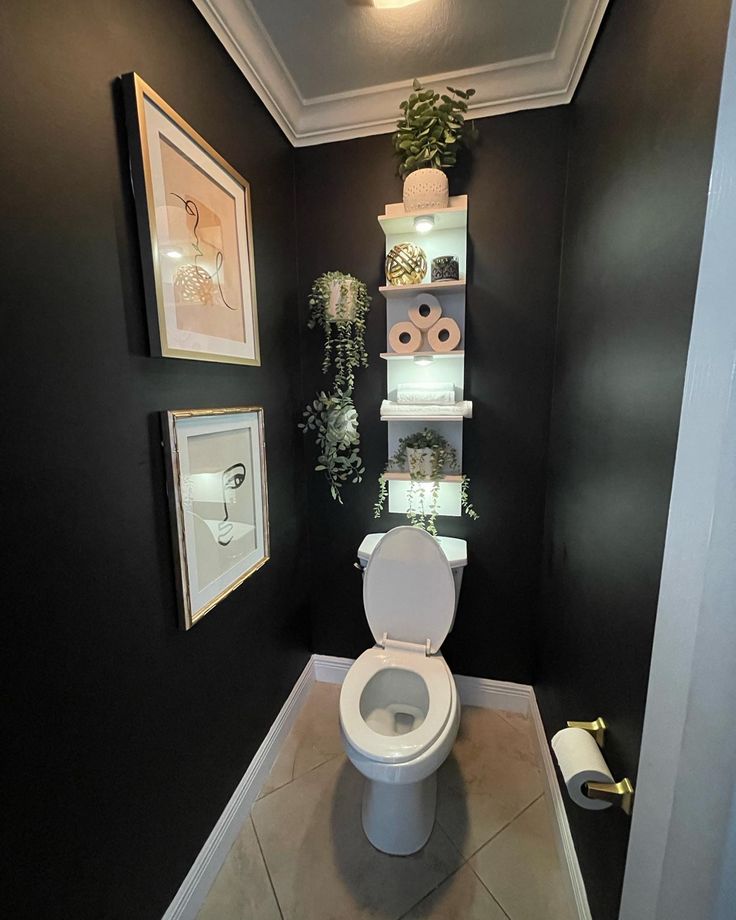 a toilet in a bathroom with black walls and pictures on the wall next to it