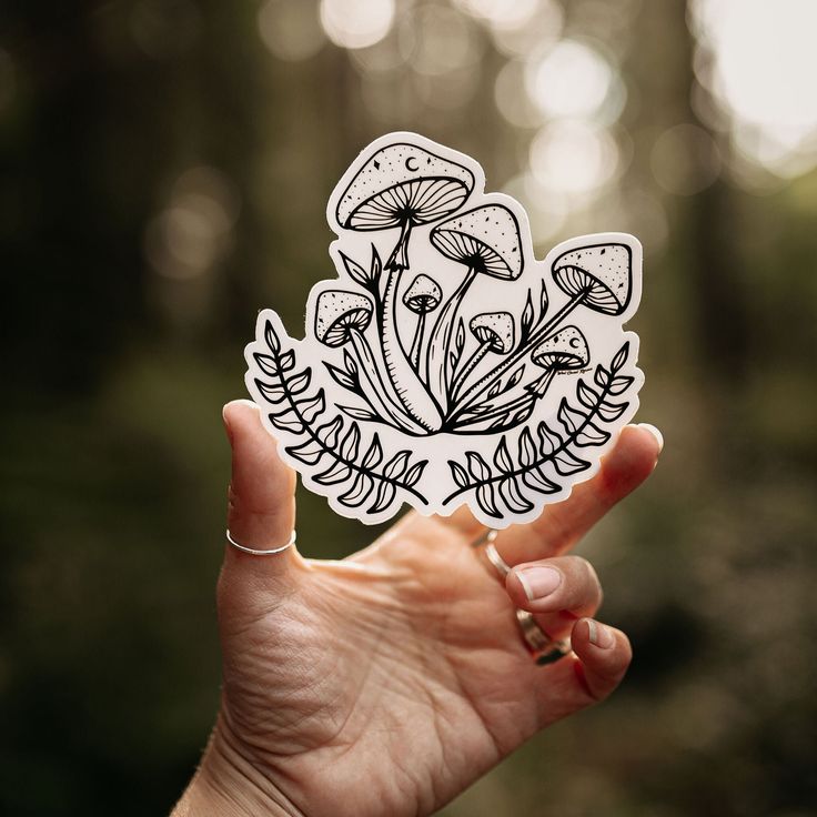 a hand holding up a sticker with mushrooms on it