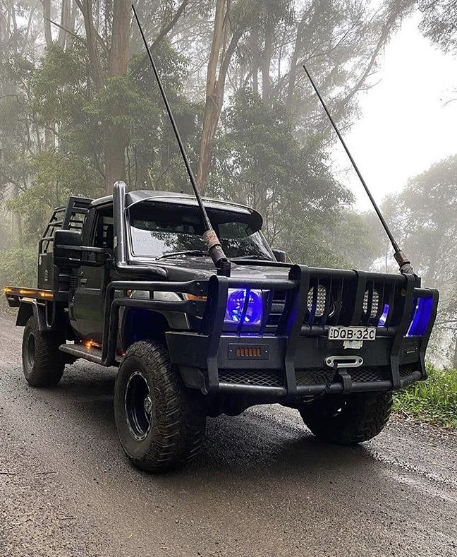 a black hummer truck parked on the side of a road in front of trees