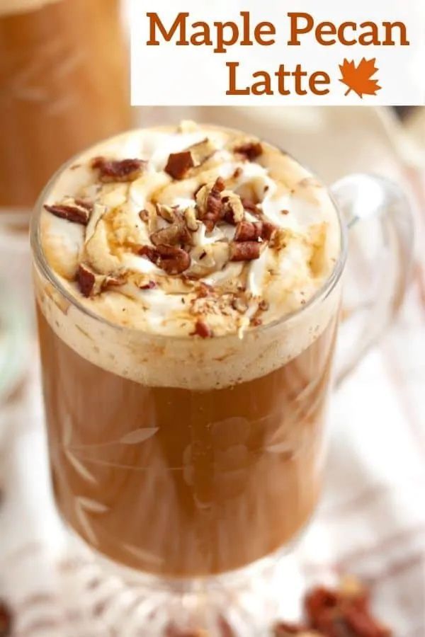 there is a cup of hot chocolate with whipped cream on top and pecans in the background