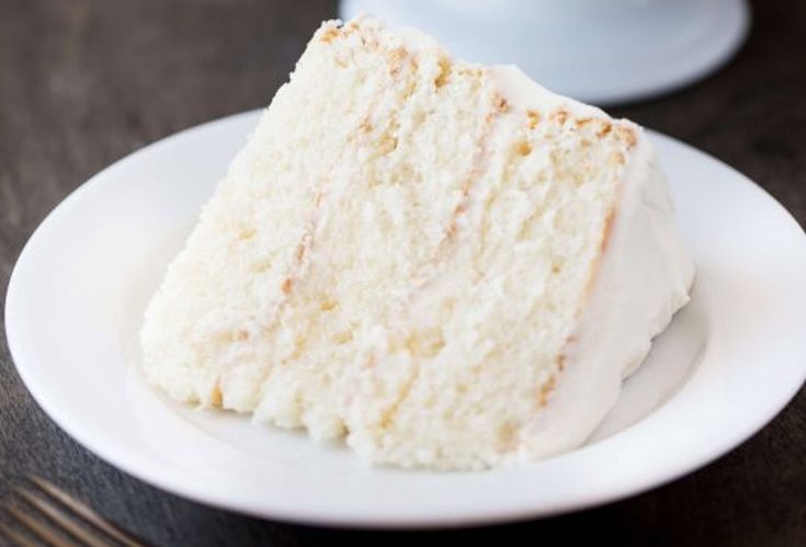 a piece of cake sitting on top of a white plate next to a coffee cup