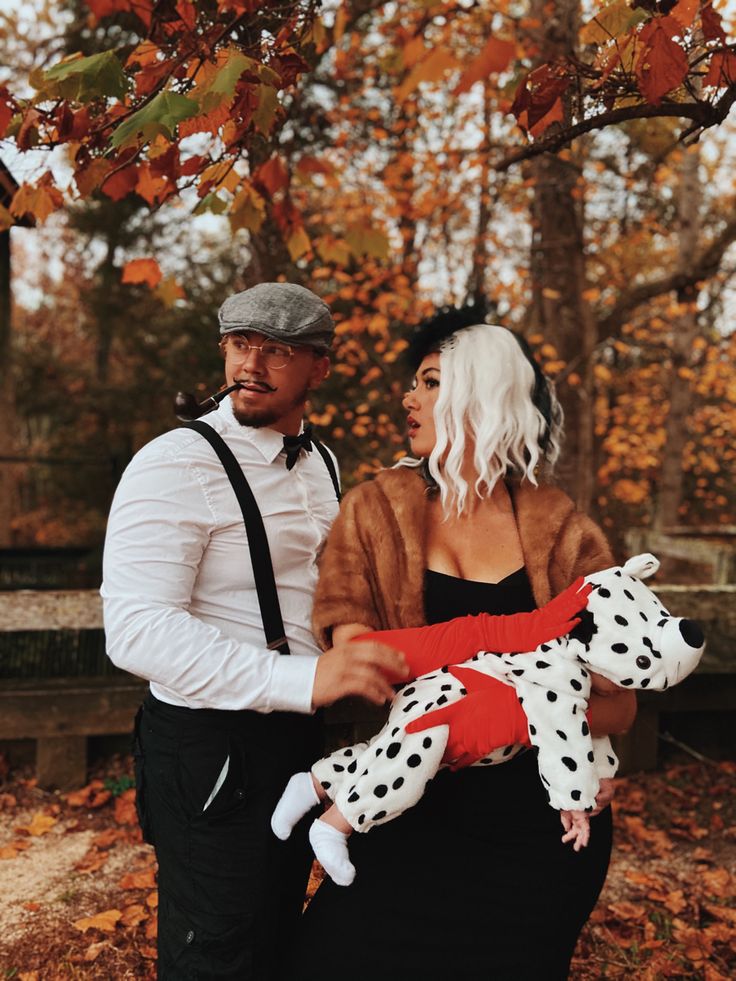 a man and woman dressed up as dalmatian dogs in front of a tree