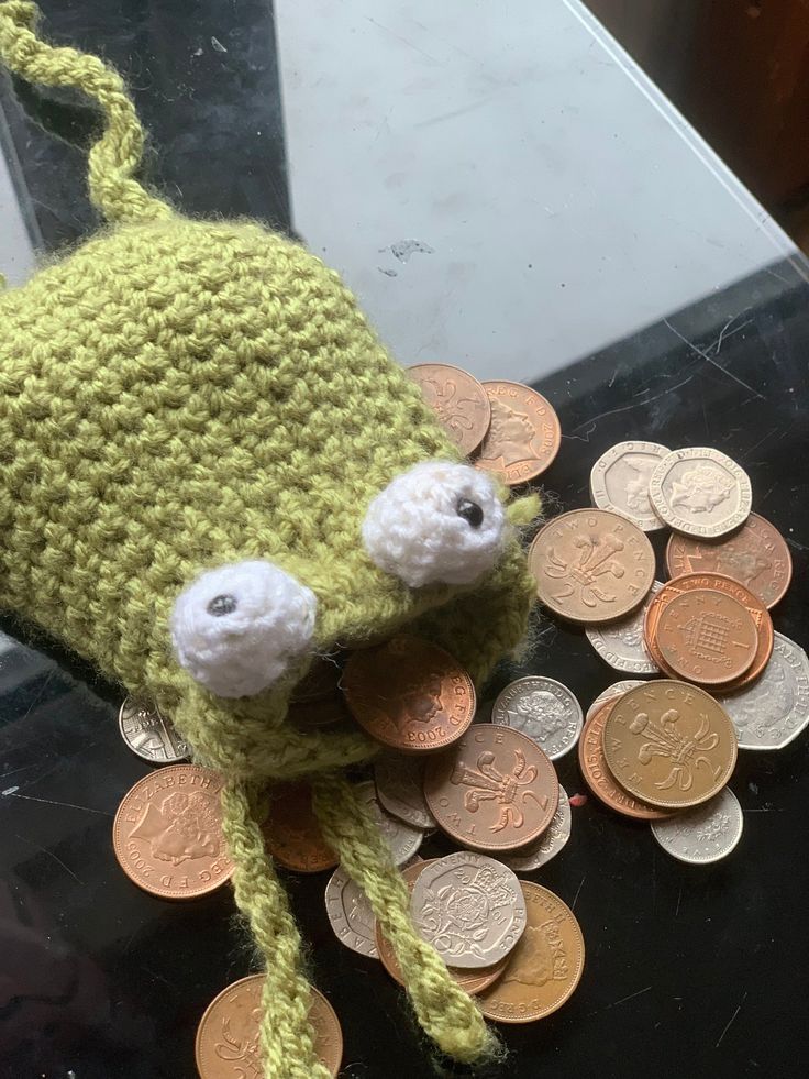 a crocheted hat sitting on top of a pile of coins