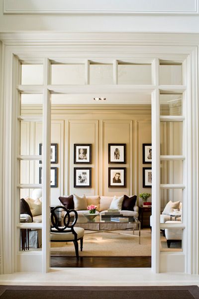 a living room filled with furniture and framed pictures on the wall above it's doorway