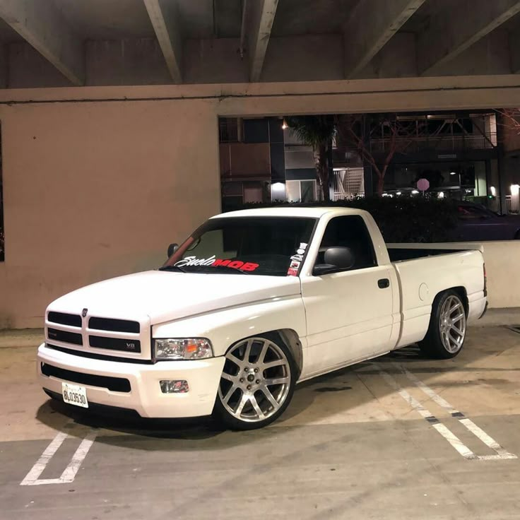 a white pickup truck parked in a parking lot next to a tall building at night