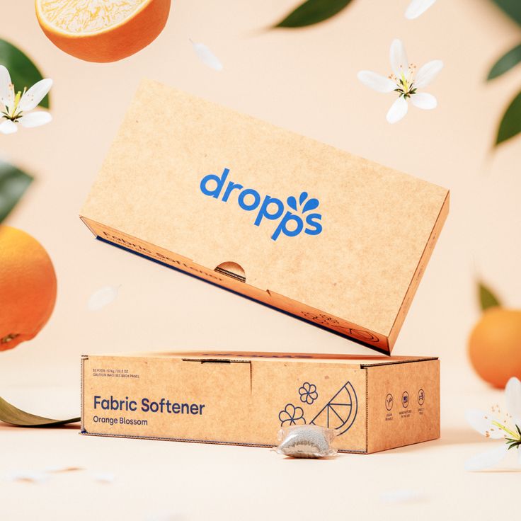 two oranges are in the air and one is on top of an unopened box