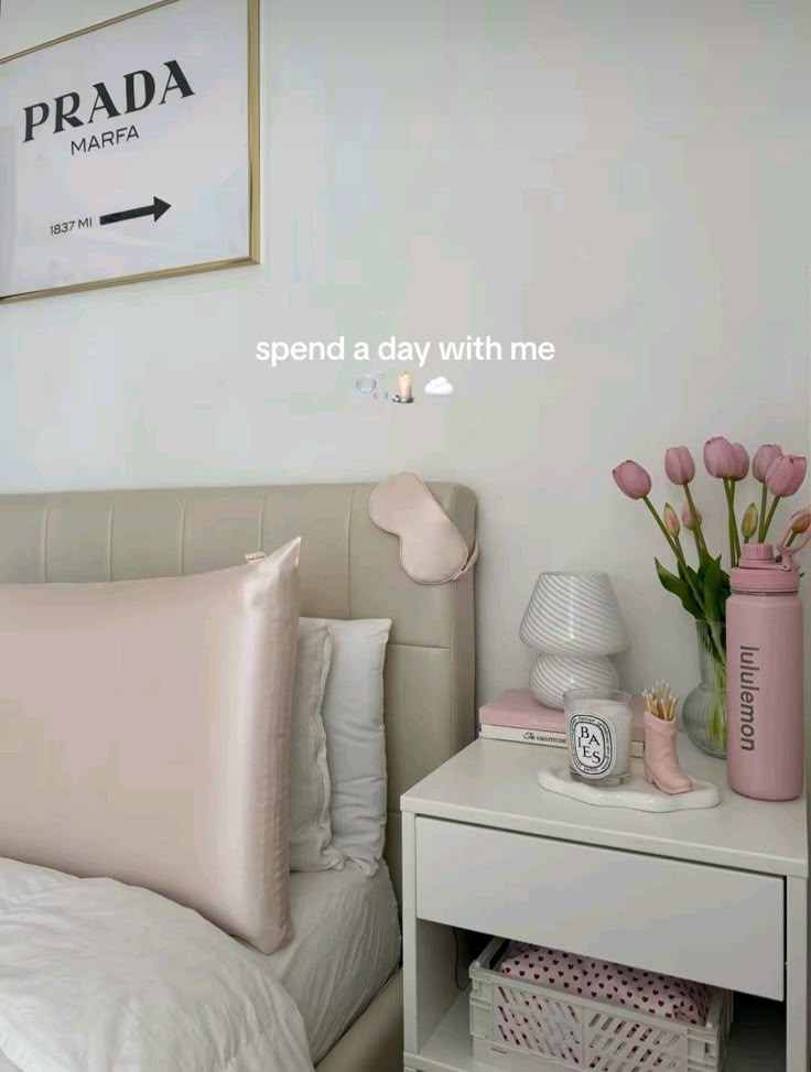 a white bed sitting next to a pink vase filled with flowers