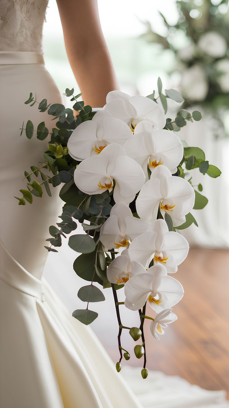 a bride holding a bouquet of white orchids