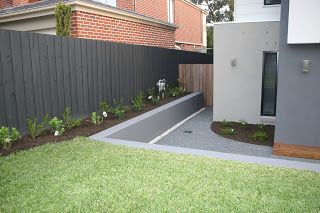 a fenced in back yard with grass and flowers on the ground next to it