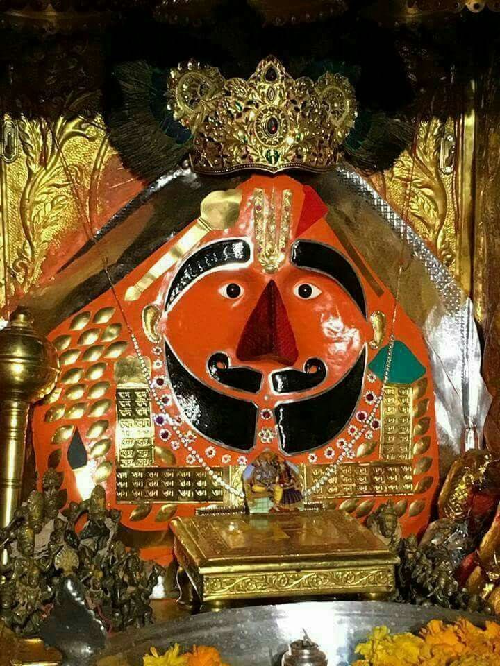 an elaborately decorated shrine with gold and red decorations on the front, surrounded by flowers