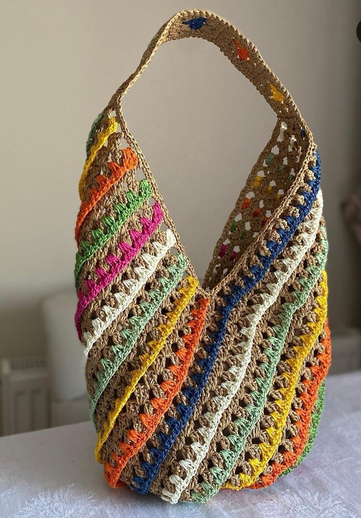 a multicolored purse sitting on top of a white table next to a wall