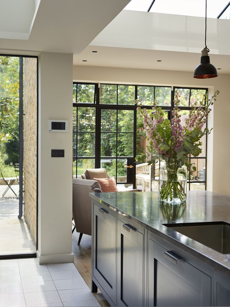 a kitchen with an island and glass doors leading to the outside patio, along with large windows