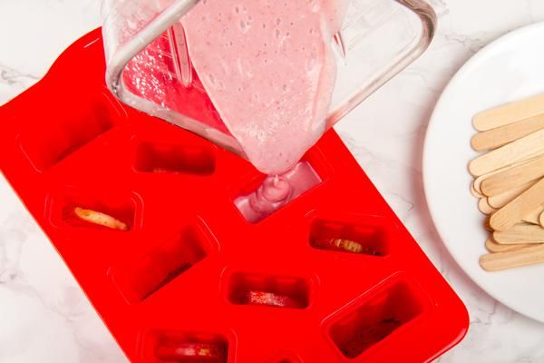 an ice tray filled with popsicles next to a white plate