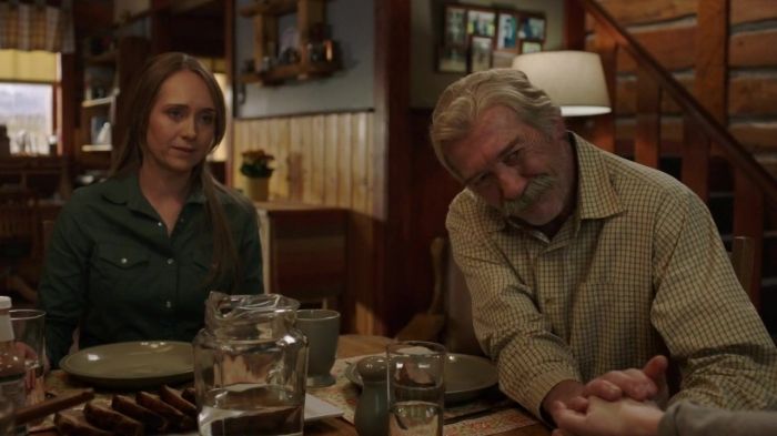 a man and woman sitting at a table in a room with wooden walls, wood flooring and shelves