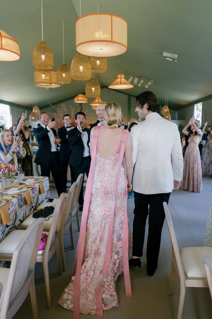 a man and woman are walking down the aisle at a formal event with other people