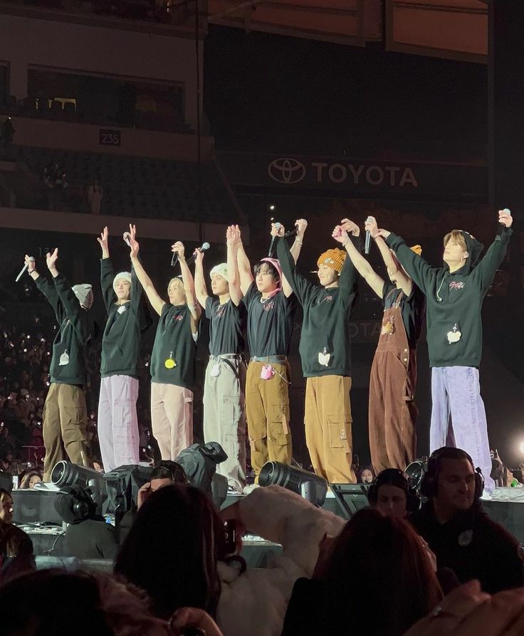 a group of people standing on top of a stage holding their hands in the air