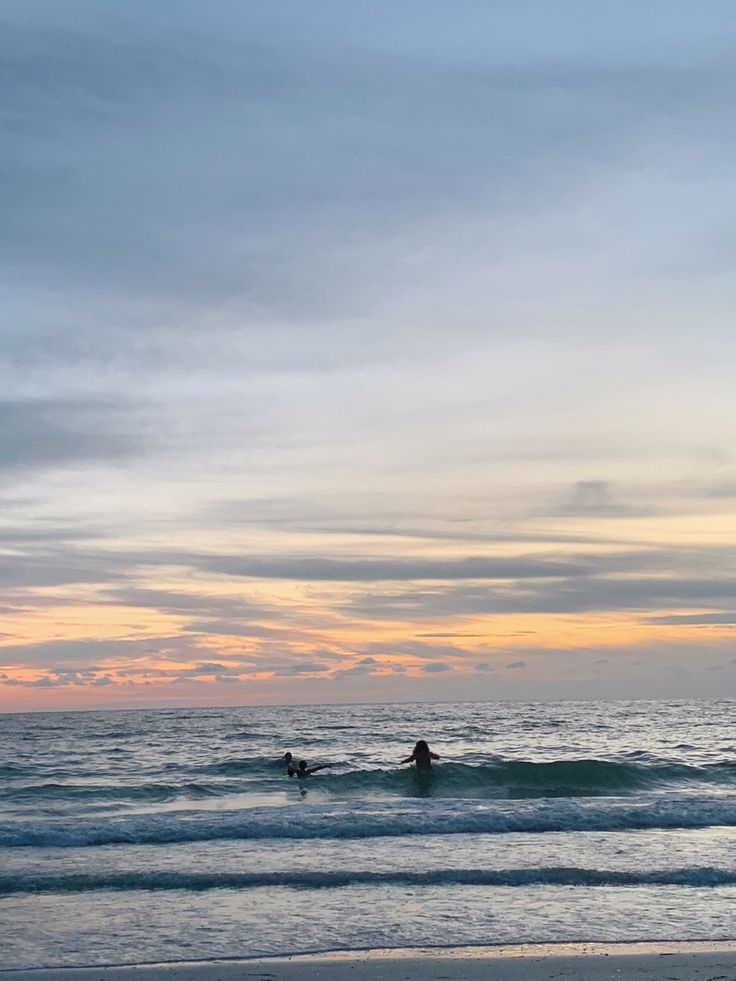 two surfers in the ocean at sunset