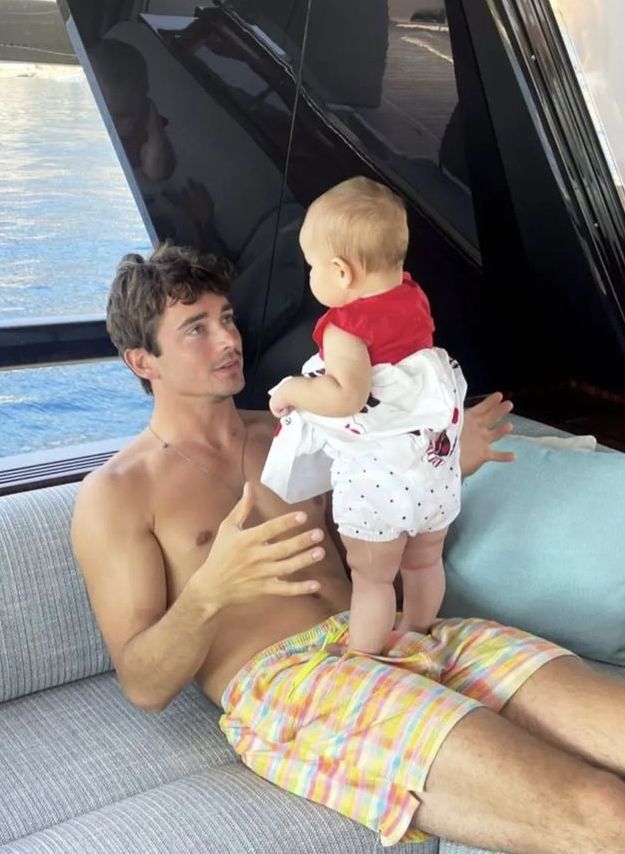 a man holding a baby while sitting on top of a couch next to a body of water