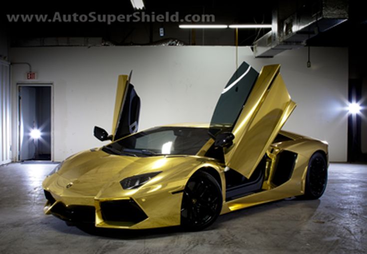 a gold colored sports car parked in a garage with its doors open and the door opened