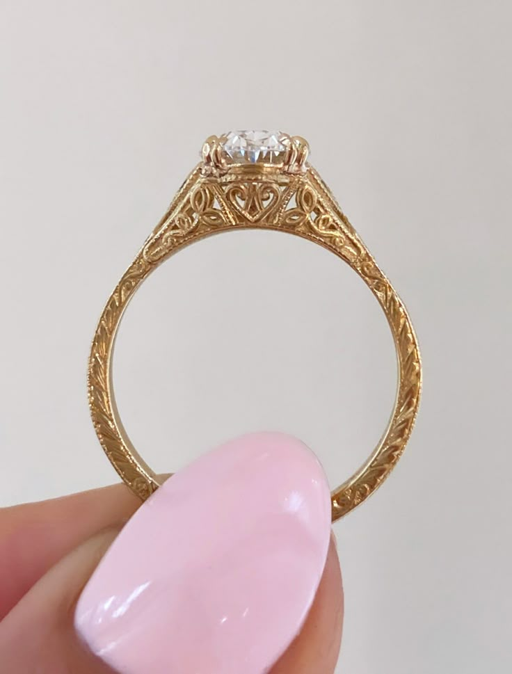 a person holding a ring with a pink stone in it's middle and a white background