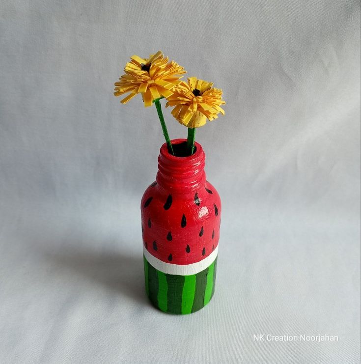 a watermelon painted vase with yellow flowers in it