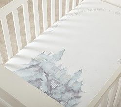 a white crib with a castle print on the side and writing on the mattress