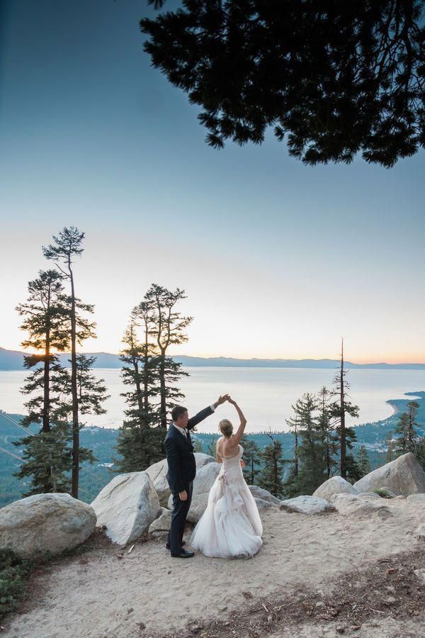 a bride and groom dancing on top of a mountain