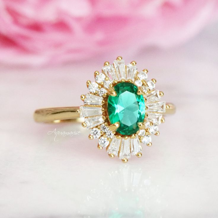 Beautiful Vintage Inspired Emerald Ring ►Base Metal: Sterling Silver (925) ►Plating: 14K Yellow Gold ►Accented With Simulated Diamonds (CZ) ►Average band width: 1.7 mm. ►Style: Art-Deco Center Stone: Emerald Gemstone Creation: Simulated Stone Shape: Oval Gem size: 7.0 x 5.0 mm Carat Weight: 0.76 ct. (Approx.) ✓ 100% Nickel-Free ✓ Hypoallergenic ✓ Comfort Fit ✓ Free Ring Box ✓ Free USA Shipping ►Please be aware that plated jewelry can wear off over time, if this is a concern we would suggest goin Heirloom Emerald Ring With Halo Design, Timeless Emerald Anniversary Ring, Timeless Emerald Wedding Anniversary Ring, Timeless Cubic Zirconia Emerald Ring For Anniversary, Classic Yellow Gold Emerald Ring With Halo, Heirloom Yellow Gold Emerald Ring With Halo Design, Timeless 14k Gold Emerald Wedding Ring, Heirloom Gold Emerald Ring With Halo Detail, Heirloom Gold Emerald Ring With Halo