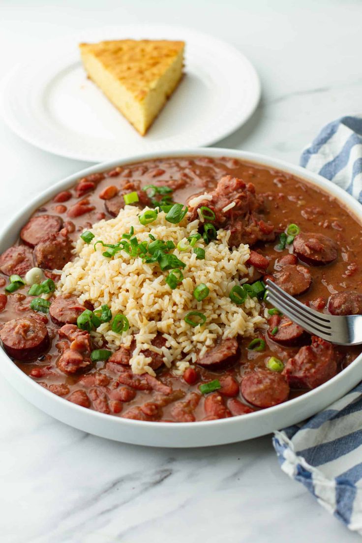 a white bowl filled with chili and rice next to a slice of cheesecake on a plate