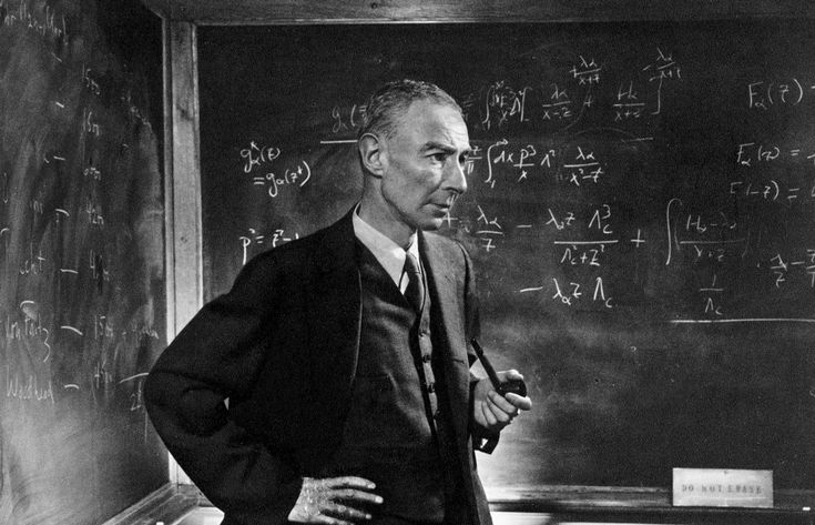 a man standing in front of a blackboard with writing on it