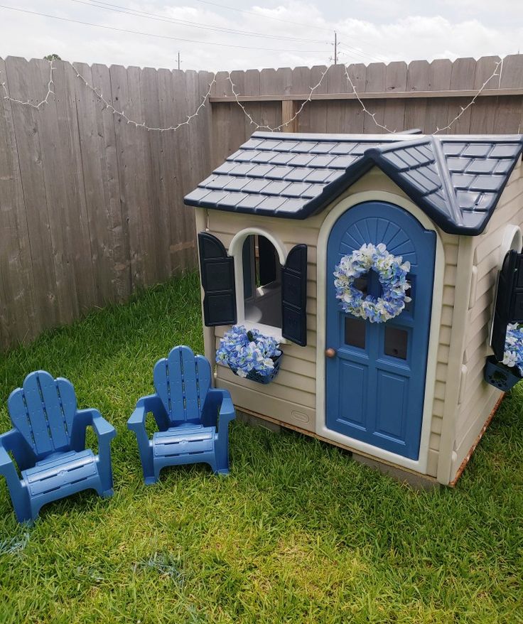 a little house with blue chairs in the yard