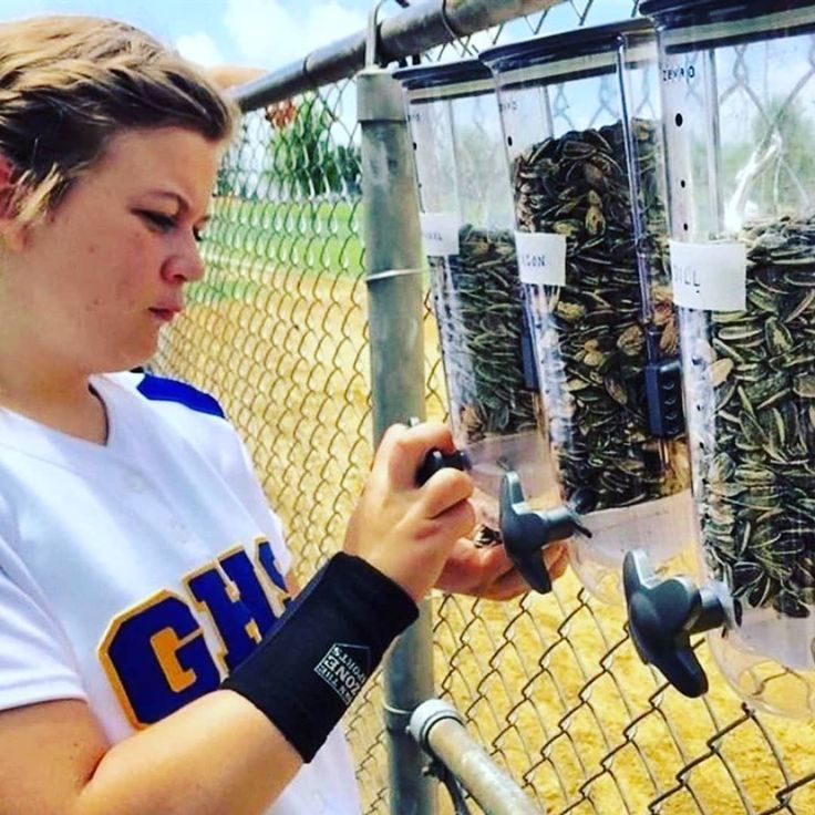 a girl is holding something in her hand and looking at it while standing next to a fence