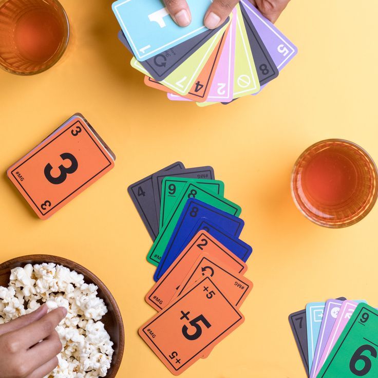 someone is playing with their numbers and counting cards on the table next to some bowls of popcorn