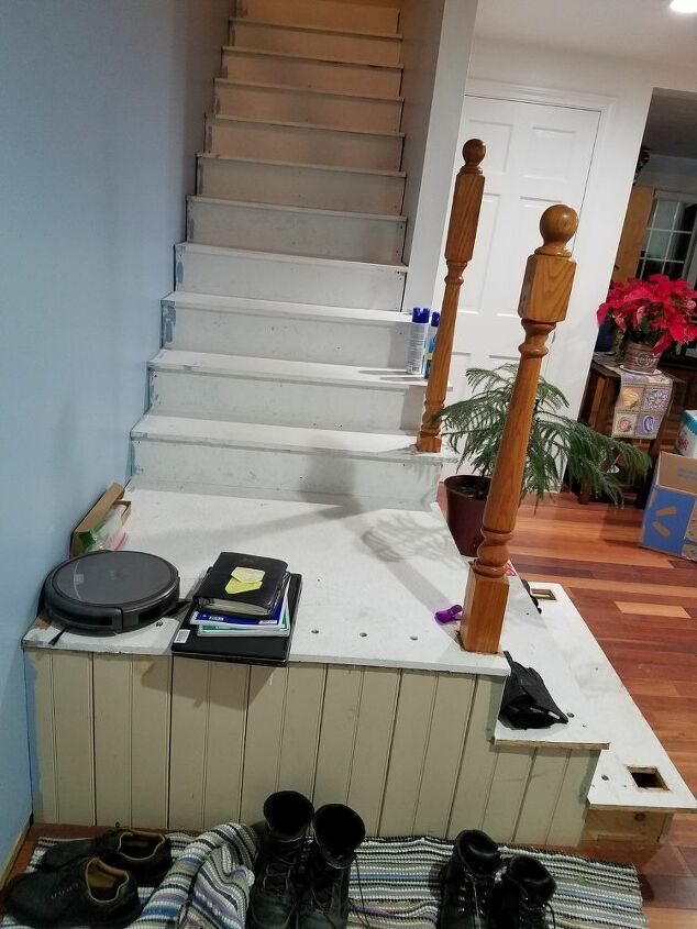 shoes are sitting on the floor in front of a stair case next to a potted plant