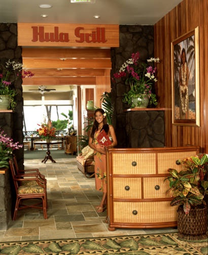 a woman standing in front of a hotel lobby filled with furniture and flowers on display