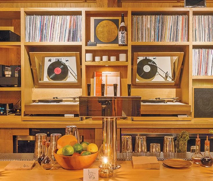 a wooden table topped with oranges next to bookshelves filled with vinyl records