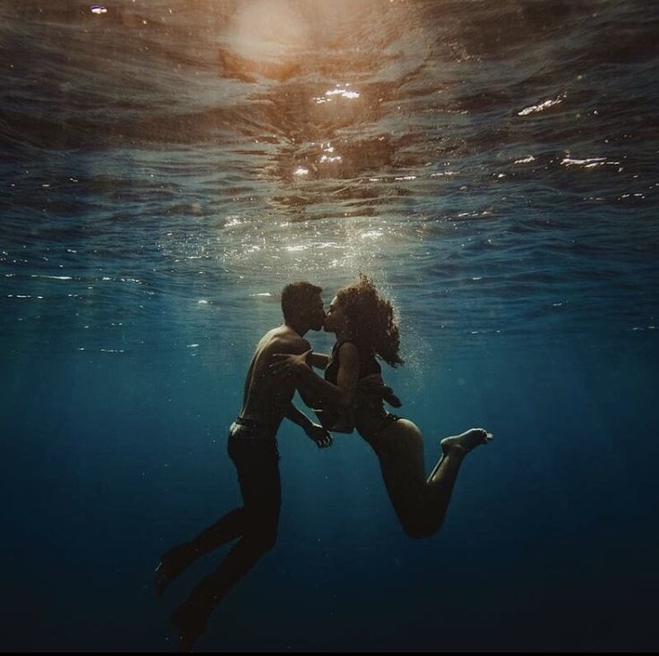 a man and woman kissing under the water