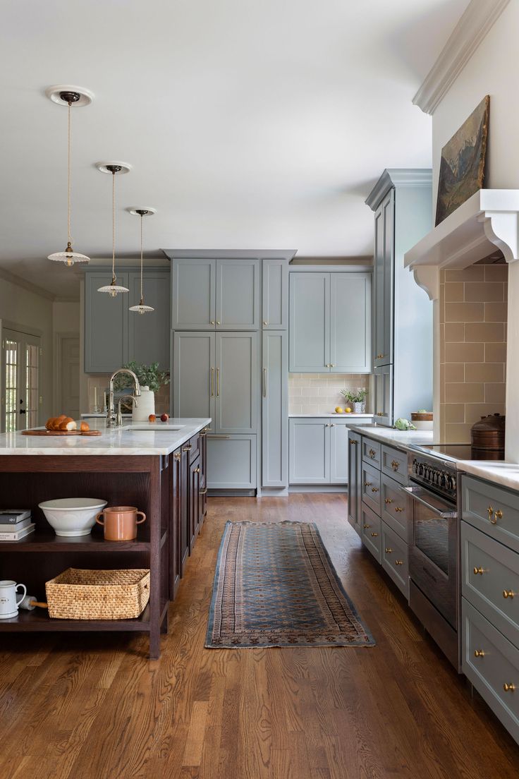 a large kitchen with wooden floors and gray cabinetry, along with an island in the middle