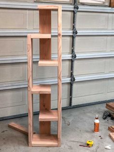 some shelves in a garage with tools on the floor and one shelf leaning against the wall